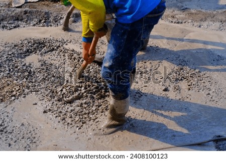 Industrial Photography. Construction work activities. Workers are hoeing and mixing cement with sand and stones for cement castings. Bandung - Indonesia, Asia