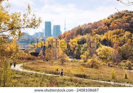 Autumn view of Weston Family Quarry Garden, a part of Valley Brick Works historic site, with hazy silhouettes of skyscrapers and CN Tower of Downtown Toronto in background Royalty-Free Stock Photo #2408108687