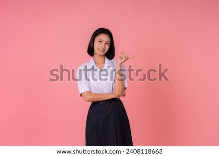Asian teenage female student Smiling and pointing at the presentation The world's educational presenter has famous schools and tutoring institutes. Taking photos in a pink background studio