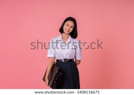 Asian teenage female student, smiling sweetly, has a school bag. She is posing Become a world education presenter with famous schools and tutoring institutes. Taking photos in a pink background studio