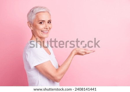 Photo portrait of lovely senior lady hold empty space demonstrate object wear trendy white garment isolated on pink color background