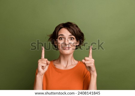 Photo of cheerful nice girl dressed orange t-shirt in glasses indicating at discount empty space isolated on khaki color background