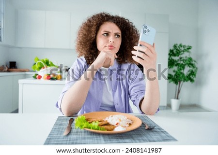 Photo of doubtful suspicious lady dressed purple shirt eating lunch reading news modern gadget indoors house kitchen Royalty-Free Stock Photo #2408141987