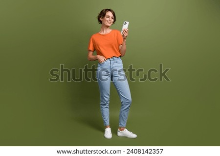 Full size photo of smart cheerful woman wear stylish t-shirt in glasses read post on smartphone isolated on khaki color background