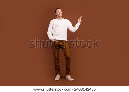 Full length photo of dreamy charming man wear white sweater showing finger looking empty space isolated brown color background