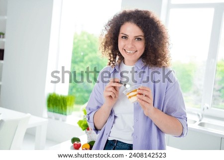 Photo of shiny cheerful lady dressed purple shirt enjoying sweet ice cream smiling indoors house kitchen