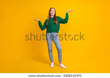 Full body photo of young blonde girl model holding two arms looking at advantage more profitable offer isolated on yellow color background