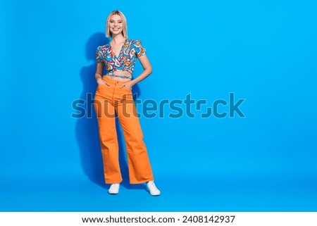 Portrait of good mood pretty cute girl wear stylish shirt orange pants holding arms in pockets isolated on vivid blue color background