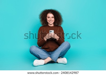 Full size photo of pretty young girl sit floor hold telephone ecommerce wear trendy brown outfit isolated on cyan color background