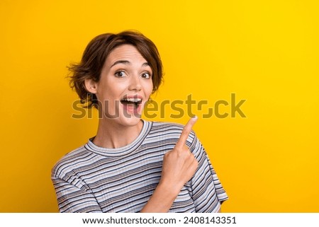 Photo of overjoyed astonished woman with bob hairdo dressed t-shirt directing at offer empty space isolated on yellow color background