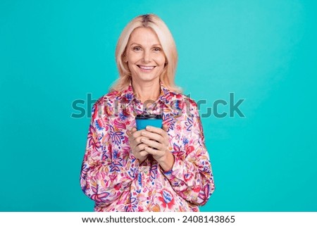 Photo of charming sweet woman dressed print shirt smiling enjoying tasty coffee isolated turquoise color background
