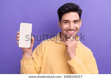 Photo portrait of attractive young man hold white screen device dressed stylish yellow clothes isolated on purple color background