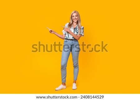 Full length photo of adorable woman wear stylish blouse denim pants indicating at discount empty space isolated on yellow color background