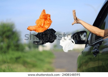 female driver's hand throwing plastic waste on the highway.  bad behavior and habits that damage the environment. Royalty-Free Stock Photo #2408148595