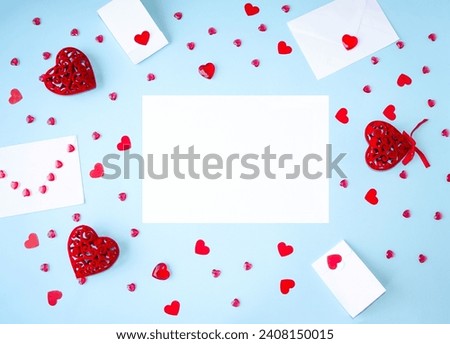 Blue background, Valentine's Day flat lay, copy space for text, holiday gifts frame, envelope and red hearts, white sheet of paper. Concept of love, romance, close relationships