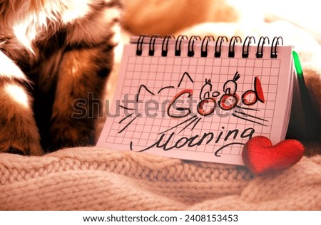 Text Good Morning on paper, notepad and rose flower. Motivation. Pretty cute kitten relaxing on the window sill. Tabby cat. Funny pets. Atmospheric mood