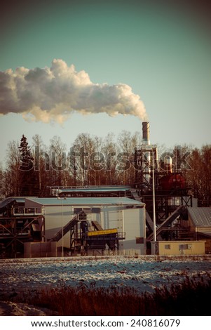 industrial park with chimney and white smoke on blue sky - retro vintage look