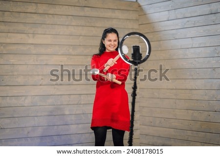 a woman in a bright red dress, smiling and juggling white hammers. She stands on the 360 photobooth platform,