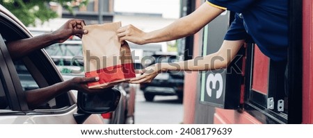 Hand Man in car receiving coffee in drive thru fast food restaurant. Staff serving takeaway order for driver in delivery window. Drive through and takeaway for buy fast food for protect covid19. Royalty-Free Stock Photo #2408179639