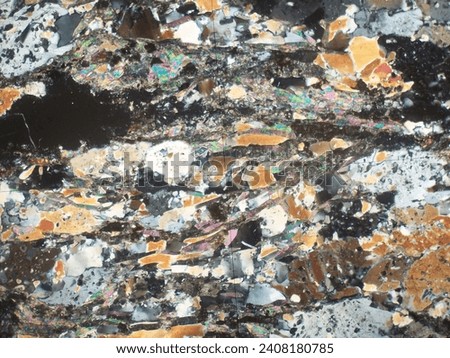 Thin section of metamorphic rocks under polarized light microscope. Geological exploration. Blurry abstract background. Royalty-Free Stock Photo #2408180785