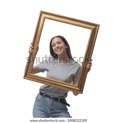 Happy young woman holding a shiny golden frame and smiling at camera