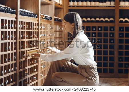 Experienced sommelier taking one of bottles from wooden cellar Royalty-Free Stock Photo #2408223745