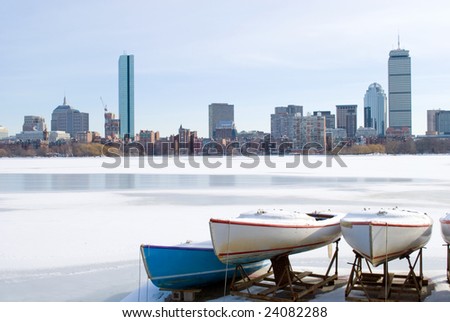 boats on frozen charles river overlooking boston skyline in the winter