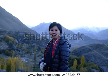 An Asian female tourist enjoying the view of Hunza Valley in early morning sunrise in Gilgit-Baltistan region of Pakistan.