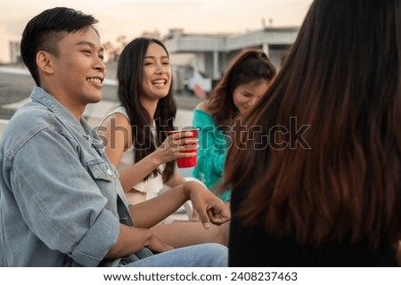 Group of happy young Asian friends partying on a rooftop bar restaurant, having fun, enjoying eating, and talking. celebration and city life concepts
