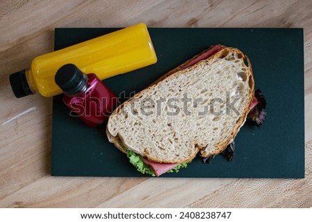 Hamburger with lettuce and cheese on chopping wooden board with juice bottle on table