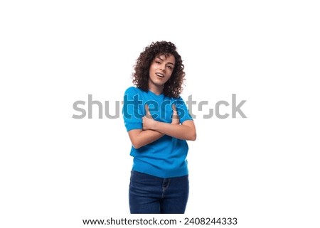 a young woman with a curly hairstyle above her shoulders in blue comfortable clothes feels confident