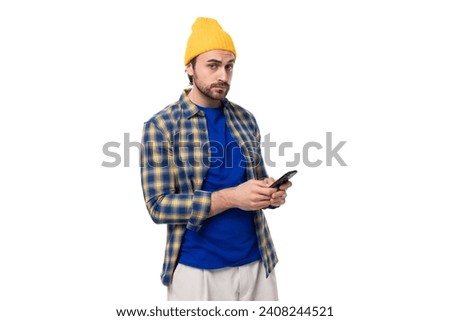 handsome young hipster man in yellow cap and shirt chatting in smartphone on white background with copy space