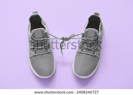 Stylish grey sneakers on purple background
