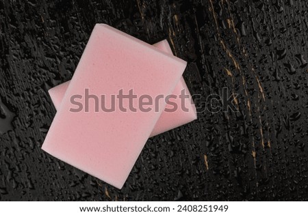 Melamine sponge on a black wet background. Beautiful drops of water around a melamine sponge. Royalty-Free Stock Photo #2408251949
