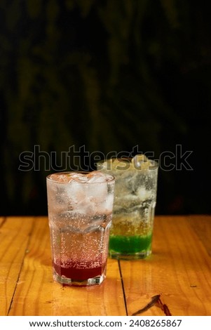 italian red fruit and green apple soda with ice under wooden background