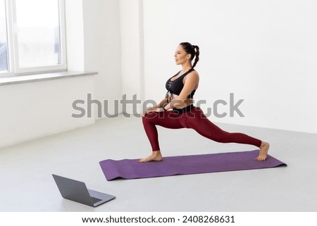Fit sporty young woman doing plank online workout exercise at home. Active healthy girl enjoy sport pilates yoga fitness training on laptop computer stretching on yoga mat watching video class.