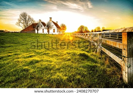A lovely image of a fence going to a house in a beautiful grassy environment