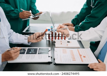 Medical team having a meeting with doctors in white lab coats and surgical scrubs seated at a table discussing a patients working online using computers in the medical industry on the black desk
