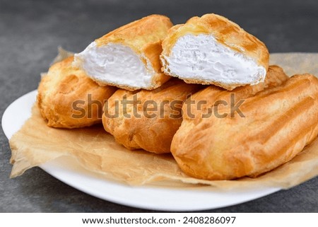 French eclairs filled with vanilla cream on gray background.