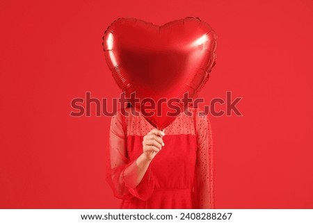 Woman with heart-shaped air balloon for Valentine's day on red background Royalty-Free Stock Photo #2408288267