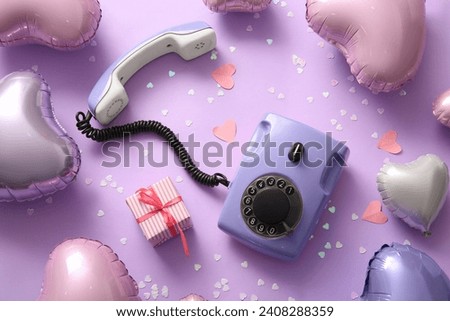 Composition with vintage telephone, heart-shaped balloons and gift for Valentine's Day celebration on color background