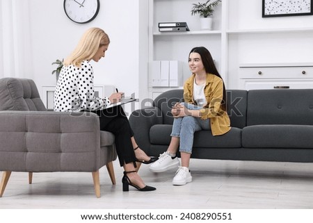 Psychologist working with teenage girl in office Royalty-Free Stock Photo #2408290551