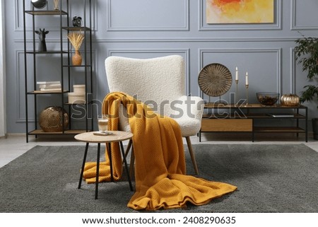 Living room interior with comfortable armchair, blanket and side table Royalty-Free Stock Photo #2408290635