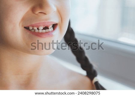 toothless smile of a girl, a baby tooth has fallen out, her face is not visible, anonymous. Royalty-Free Stock Photo #2408298075
