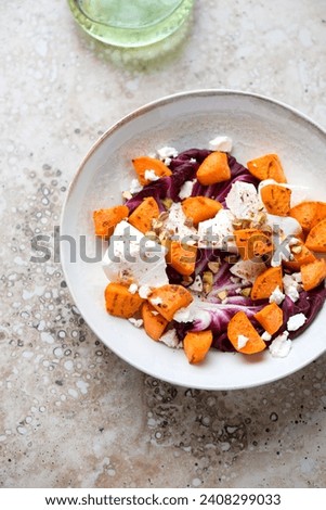 Plate with roasted sweet potato, radicchio and feta cheese, vertical shot on a beige granite background, selective focus