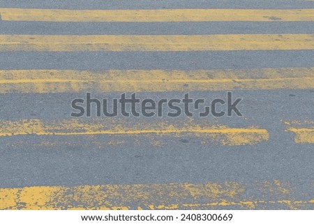 It is weathered yellow pedestrian crossing. This is aged zebra crossing. It is the close up view of yellow safety walkway.