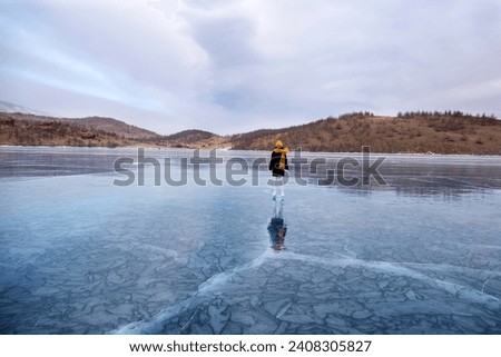 A young athletic girl is skating on the transparent ice of the frozen Lake Baikal. Active winter holidays.