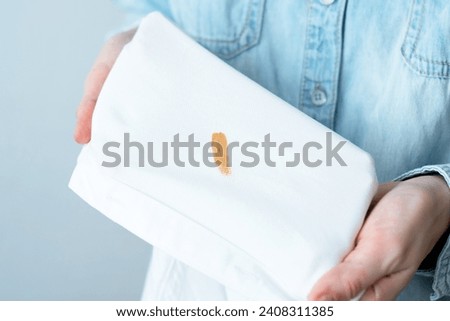Cosmetic stains on the white clothes. The housewife evaluates the stain before removal. Liquid foundation cream. daily life stain and cleaning concept. top view. High quality photo