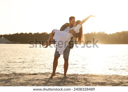 Beautiful couple dancing and kissing near river on sunny day