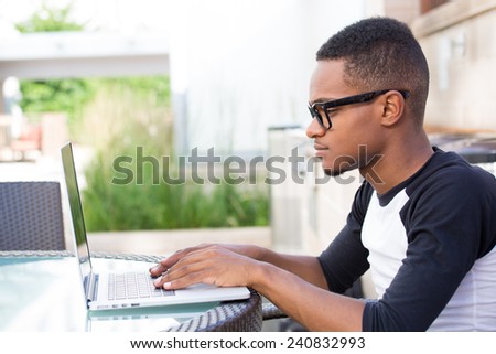 Closeup portrait, young nerdy man in big black glasses surfing the web on personal silver laptop, isolated outside outdoors background
